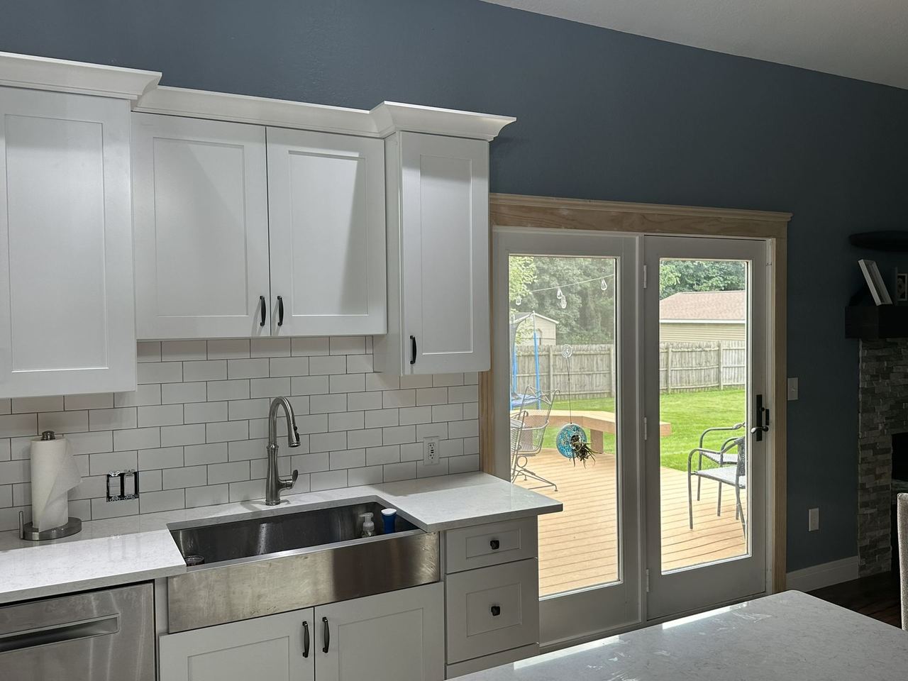 Bright remodeled kitchen with white shaker cabinets, subway tile, and French doors opening to a backyard deck
